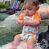 Billy joined the competition — help win amazing prizes! baby, child, water, swimsuit, orange_clothing, dinosaur_pattern, tattoo, arm, rock, outdoor, pool, flag, house, greenery, summer, sitting, person, nature, foot, hand