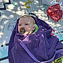 baby, blanket, calm, child, clothing, face, grass, green, infant, mat, outdoor, pacifier, pattern, purple, relaxing, shadow, striped, sunlight, towel, wrapped