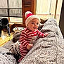 Jayden is registered to the contest to win money with this photo: baby, blanket, child, couch, daylight, festive, furniture, gray_couch, hat, holiday, home, indoor, knit_hat, person, pom_pom, smiling, striped_clothing, toddler, window, wood_floor