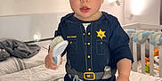 Jayden joined the competition — help win amazing prizes! baby, bed, brush, child, crib, expression, face, framed_art, hand, indoor, lamp, nursery, pajamas, police_costume, portrait, sheriff_badge, socks, standing, toddler, toy