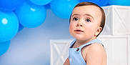 Jayden joined the competition — help win amazing prizes! baby, child, blue_balloons, romper, sitting, curious, white_floor, decorative_boxes, portrait, infant, cute, indoor, celebration, studio_lighting, soft_skin, young_child, happy, isolated, playful, background