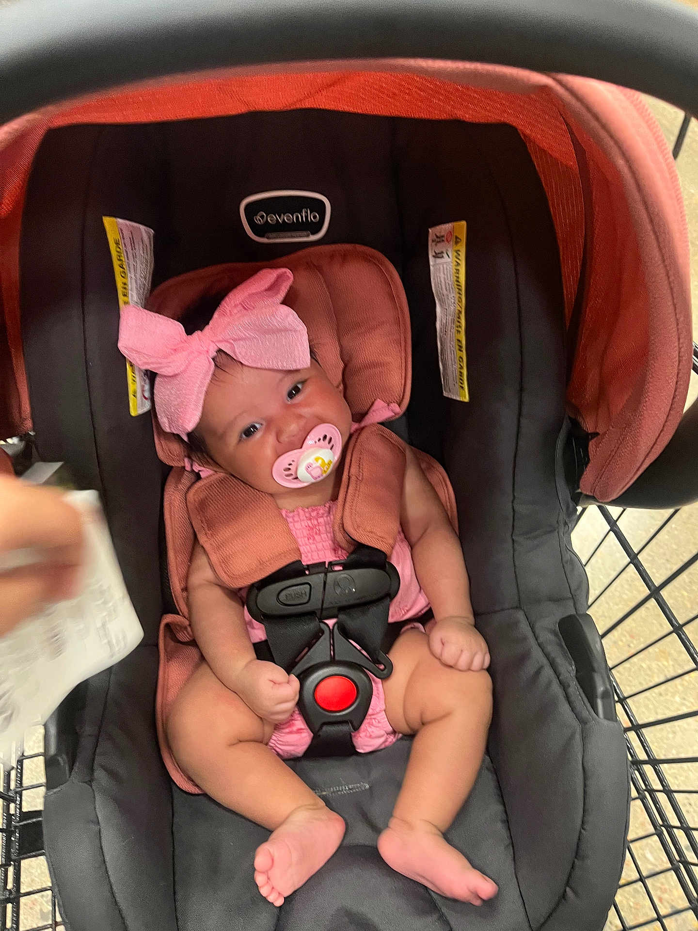 Rhaenyra joined the competition — help win amazing prizes! baby, infant, car_seat, pacifier, bow, pink_clothing, shopping_cart, child, cute, strapped_in, seatbelt, indoor, person, footwearless, expression, headwear, sitting, closeup, happy, retail