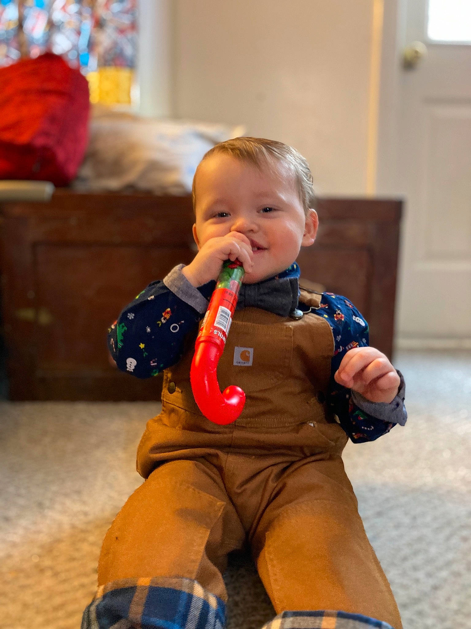 Calvin is registered to the contest to win money with this photo: arm, baby, baby_toddler_clothing, cheek, child, event, eye, flooring, fun, happy, human_body, human_leg, knee, orange, person, sitting, skin, standing, tartan, thigh