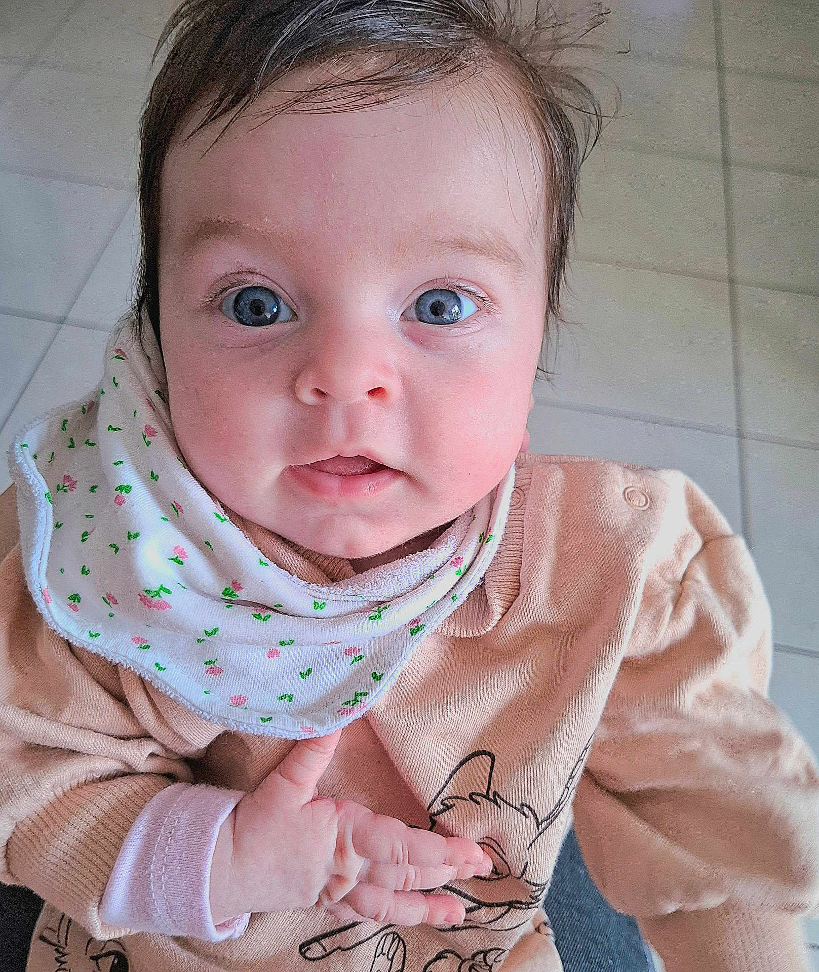 Elena participe au concours pour gagner de l'argent avec cette photo : baby, infant, blue_eyes, wide_eyes, bib, hand, onesie, portrait, cute, skin, face, hair, tile_floor, indoor, close_up, looking_at_camera, tiny_fingers, expression, soft_lighting, awake