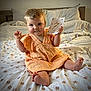 baby, bed, blanket, card, child, cozy, cute, dress, fabric, face, foot, hair, hand, indoor, infant, pattern, pillow, sitting, smile, soft