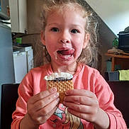 Alana participe au concours pour gagner de l'argent avec cette photo : child, curly_hair, ice_cream, messy_face, pink_shirt, unicorn, kitchen, table, happy, licking, food, snack, person, indoor, smile, cute, young, holding, dessert, playful
