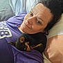 woman, dog, bed, pillow, sleeping_dog, purple_shirt, laying_down, indoor, pet, resting, cute, companion, relaxation, nap, human, animal, casual, closeup, face, comfort