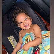 Amir joined the competition — help win amazing prizes! toddler, child, smiling, curly_hair, car_seat, blanket, cartoon_characters, indoor, baby, cute, happy, seat_belt, foot, skin, person, portrait, infant, car, sitting, playful