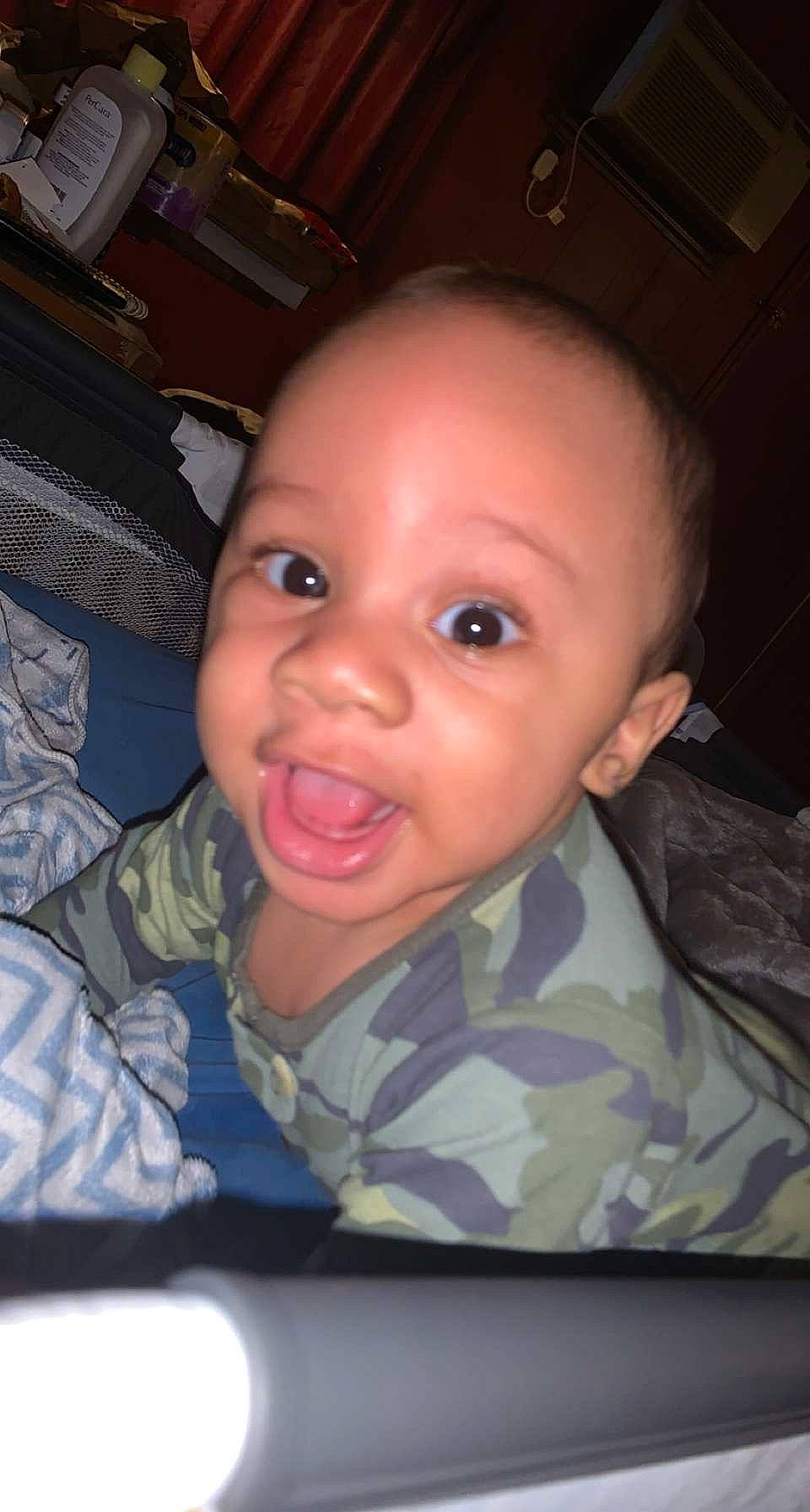 Amaree is registered to the contest to win money with this photo: baby, cheek, child, comfort, ear, eye, eyebrow, forehead, fun, gesture, iris, military_camouflage, mouth, nose, organ, person, sitting, skin, smile, soldier