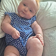 Delilah Denise is registered to the contest to win money with this photo: baby, infant, child, blue_outfit, floral_pattern, pillow, soft_texture, red_hair, curious_expression, indoors, couch, plush, skin, legs, arms, hand, cute, chubby, portrait, relaxed