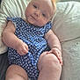 baby, infant, child, blue_outfit, floral_pattern, pillow, soft_texture, red_hair, curious_expression, indoors, couch, plush, skin, legs, arms, hand, cute, chubby, portrait, relaxed