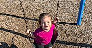 Madalyn is registered to the contest to win money with this photo: child, swing, playground, outdoor, grass, tree, bench, sunlight, woodchips, smile, sandals, summer, park, happy, girl, clothing, nature, shadow, recreation, fun