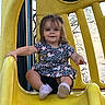 Madalyn joined the competition — help win amazing prizes! toddler, child, slide, playground, yellow_slide, dress, outdoor, smiling, happy, play, fun, trees, nature, daylight, feet, shoes, person, young_child, activity, leisure