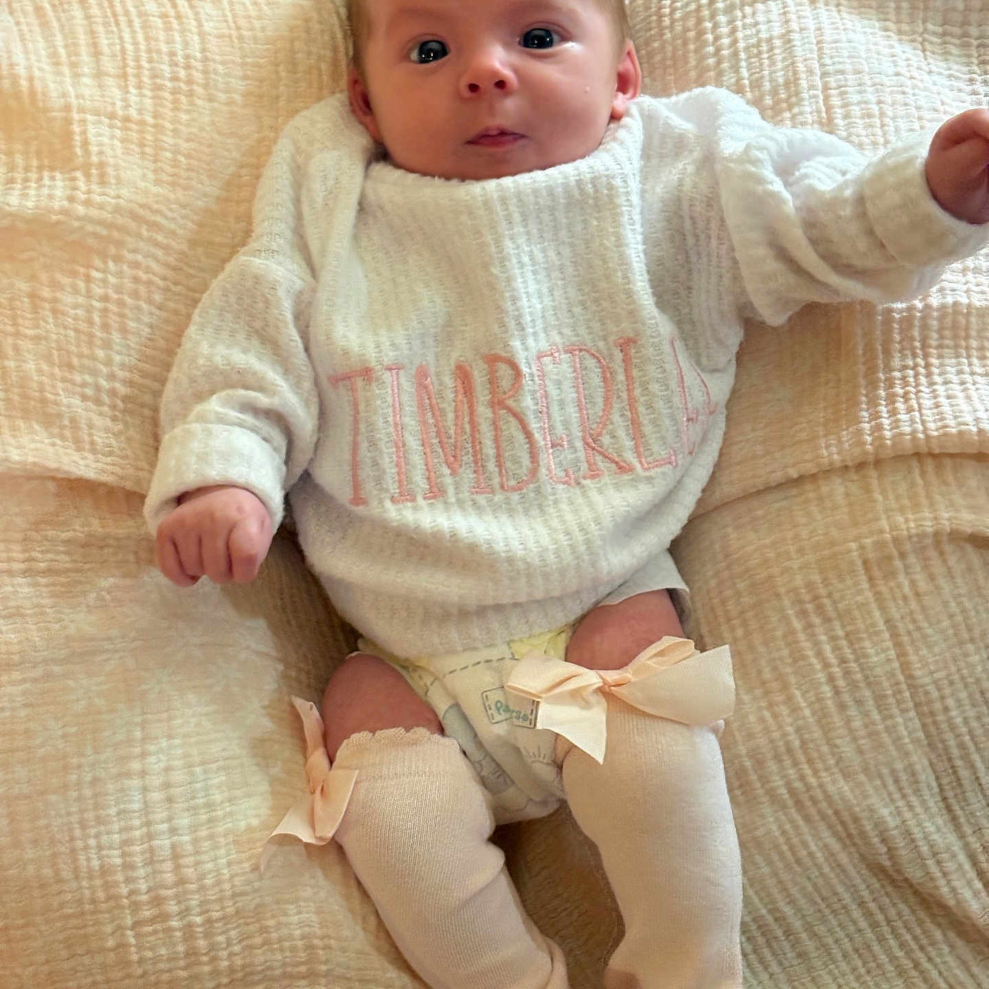 Timberlee joined the competition — help win amazing prizes! baby, infant, sweater, leg_warmers, bow, blanket, lying_down, cute, clothing, face, person, child, soft_texture, warm, cozy, indoor, newborn, adorable, expression, skin