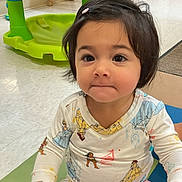 Isla is registered to the contest to win money with this photo: toddler, child, indoors, pajamas, playmat, toy, curly_hair, cute, sitting, floor, colorful, young_child, person, baby, smiling, playroom, bright, casual_clothing, expression, hair_clip