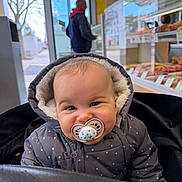 Esaïe a rejoint le concours — aidez-le/la à gagner de superbes lots ! baby, pacifier, jacket, hooded_clothing, indoor, bakery, food_display, man, woman, window, door, shopping, child, cute, portrait, cold_weather, cozy, smile, face, person