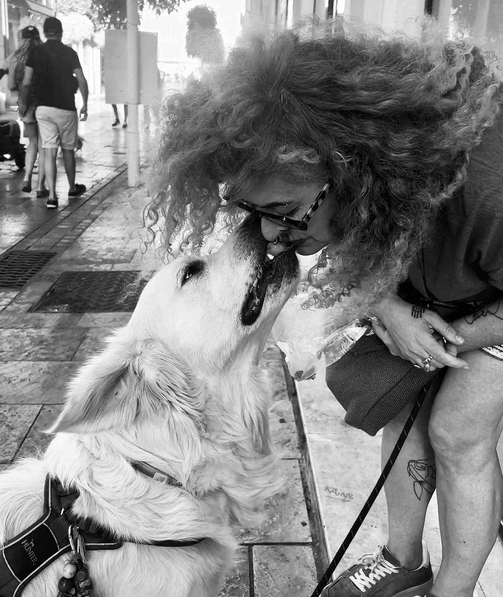 Léon a rejoint le concours — aidez-le/la à gagner de superbes lots ! dog, woman, curly_hair, glasses, sidewalk, urban, leash, love, affection, pet, street, tattoo, sneakers, black_and_white, close_up, outdoor, interaction, happy, canine, people