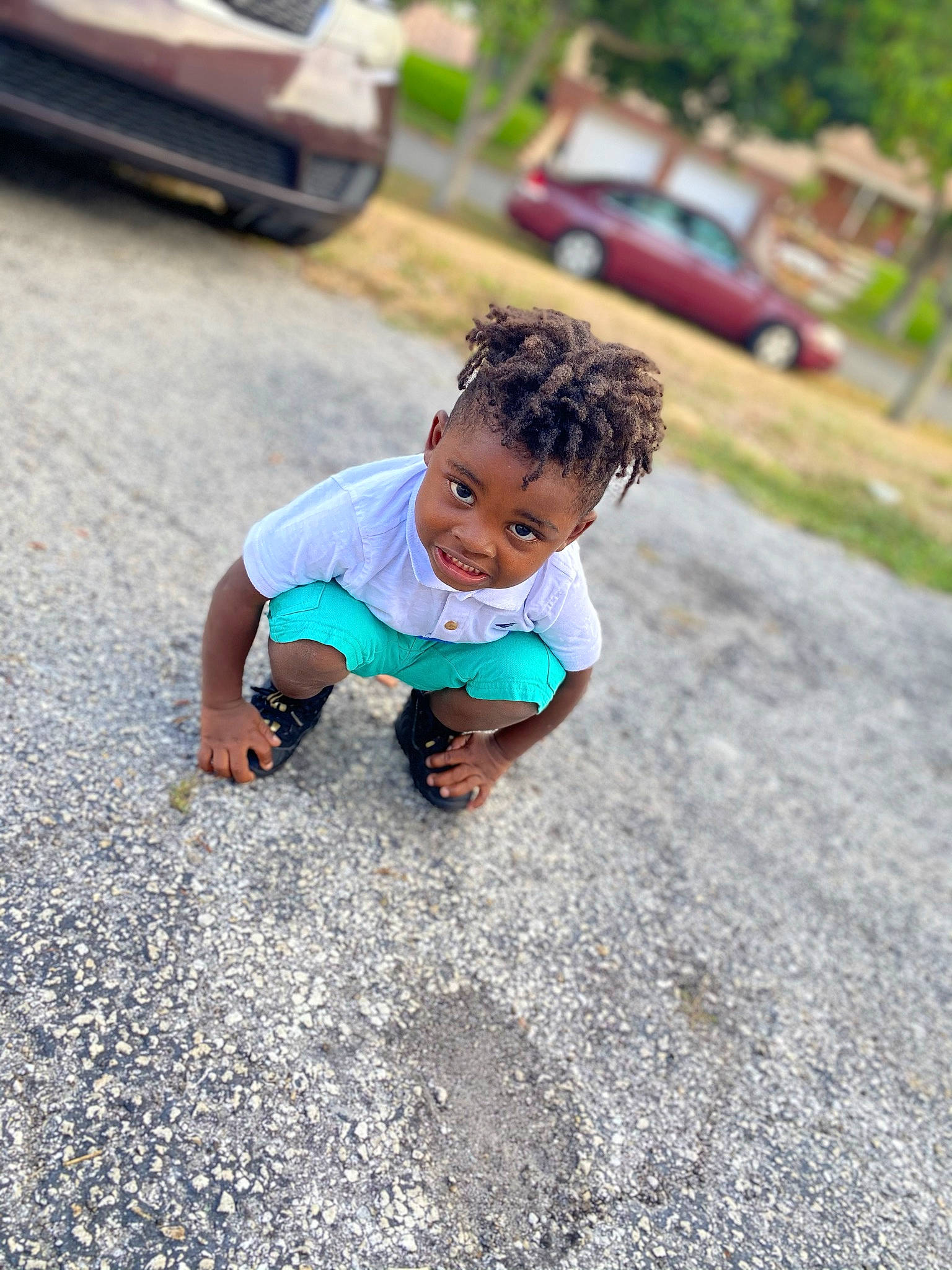 Jamari is registered to the contest to win money with this photo: asphalt, automotive_tire, baby, car, face, flooring, fun, grass, happy, leisure, person, plant, recreation, road, road_surface, sidewalk, t_shirt, tire, toddler, vehicle