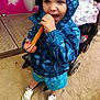child, toddler, rain_jacket, churro, snack, stroller, baby, blanket, sand, shoes, outdoor, blue_clothing, food, happy, cute, person, playground, casual, young_child, footwear