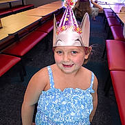 Lainey joined the competition — help win amazing prizes! child, girl, party_hat, blue_dress, smiling, indoor, bench, table, carpet, playful, celebration, birthday, crown, happy, person, people, fun, event, young, casual