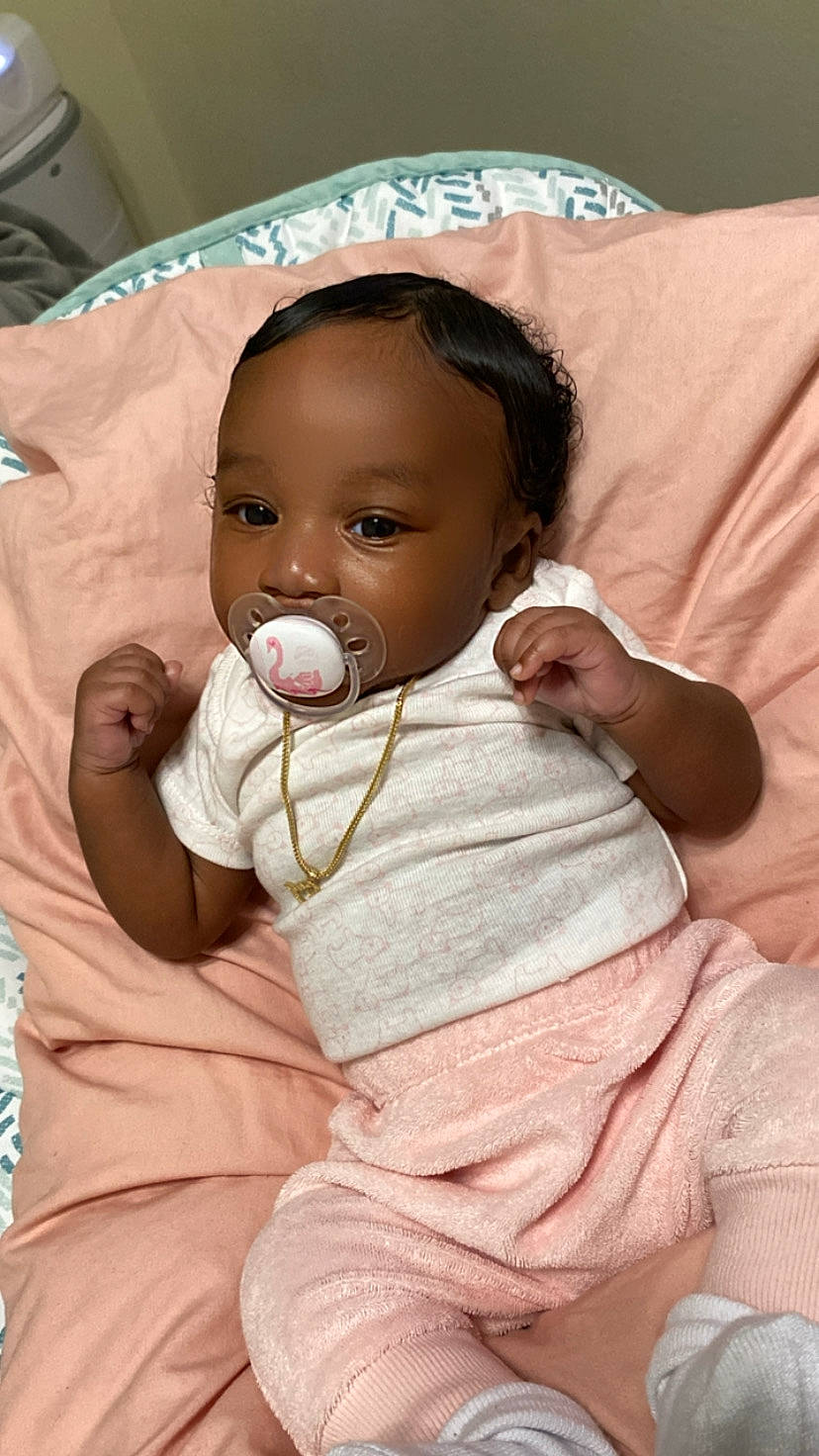 Legacy is registered to the contest to win money with this photo: baby, baby_toddler_clothing, cheek, comfort, finger, fun, gesture, happy, head, iris, linens, lip, mouth, nose, person, pink, skin, sleeve, smile, textile