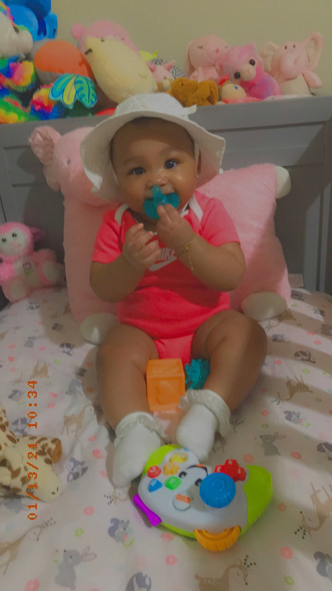 Secret is registered to the contest to win money with this photo: baby, baby_playing_with_toys, baby_products, baby_toddler_clothing, baby_toys, bed, child, foot, hat, human_body, nursery, party_supply, peach, person, pink, plush, product, stuffed_toy, sun_hat, toddler