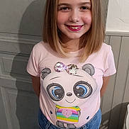 Alicia participe au concours pour gagner de l'argent avec cette photo : child, girl, smile, blonde_hair, tshirt, panda_graphic, indoor, jeans, standing, happy, casual_clothing, portrait, young, fashion, cute, person, childhood, background, shadow, wall