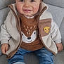 toddler, child, smiling, sitting, couch, fleece_jacket, jeans, sneakers, baby_teeth, cute, indoor, portrait, happy, clothing, face, person, casual_wear, cozy, light, comfortable