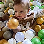child, toddler, ball_pit, plastic_balls, play_area, indoor, cute, baby, fun, toy, colorful, smiling, face, clothing, young_child, entertainment, activity, happy, person, playtime
