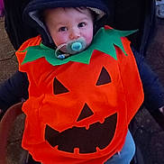 Solann participe au concours pour gagner de l'argent avec cette photo : baby, pumpkin_costume, pacifier, stroller, hood, child, cute, costume, halloween, outdoor, smiling, face, person, blue_pants, jack_o_lantern, seasonal, festive, young_child, warm_clothing, portrait