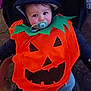 baby, pumpkin_costume, pacifier, stroller, hood, child, cute, costume, halloween, outdoor, smiling, face, person, blue_pants, jack_o_lantern, seasonal, festive, young_child, warm_clothing, portrait