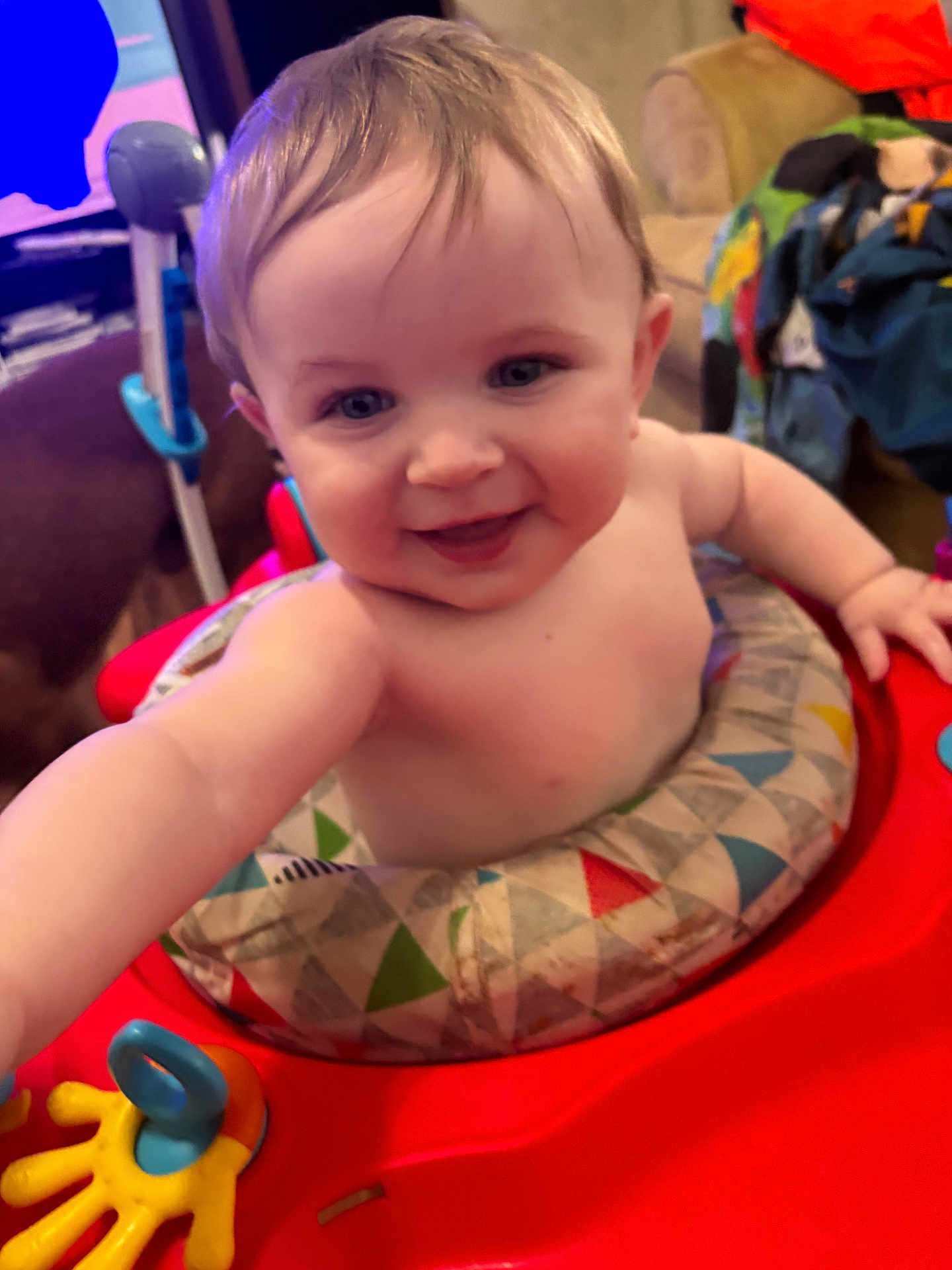 Kevin is registered to the contest to win money with this photo: baby, smile, face, child, walker, toy, indoor, person, happy, colorful, clothing, furniture, living_room, hair, skin, arm, hand, seat, cushion, expression