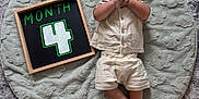 Gabriel joined the competition — help win amazing prizes! baby, infant, child, smiling, clothing, chalkboard, month, number, soft_mat, texture, wooden_frame, lying_down, cute, happy, indoors, hands, feet, portrait, young, comfortable