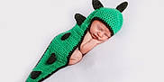 Teddy is registered to the contest to win money with this photo: baby, newborn, sleeping, crochet, green, dinosaur_costume, spikes, cute, infant, soft, white_background, peaceful, portrait, resting, child, costume, knitted, adorable, toddler, face