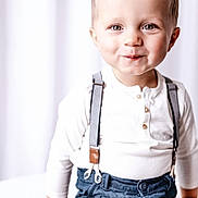Raphaël participe au concours pour gagner de l'argent avec cette photo : child, toddler, portrait, smile, suspenders, white_shirt, blue_pants, indoor, studio, curtains, hands, eyes, blond_hair, cute, fashion, buttoned_shirt, sitting, closeup, soft_lighting, high_key