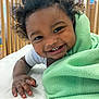 baby, blanket, child, close_up, crib, curly_hair, cute, face, green_blanket, hand, happy, indoors, person, portrait, skin, smile, teeth, toddler, white_clothing, wooden_crib