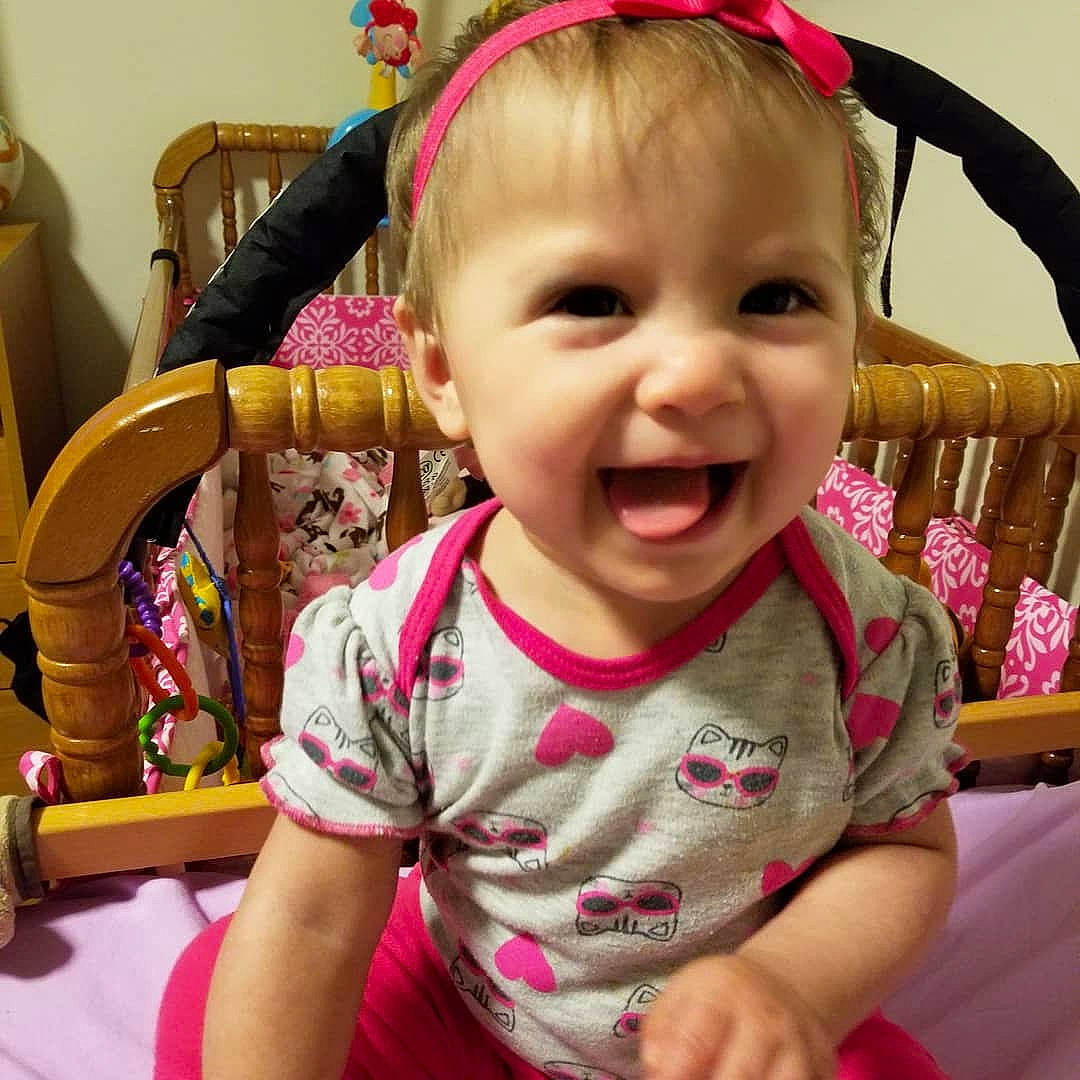 Julie is registered to the contest to win money with this photo: baby, baby_products, cheek, child, ear, eye, face, facial_expression, fun, hair_accessory, happy, head, headband, lip, organ, person, pink, product, skin, smile