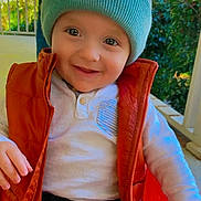 Kashton is registered to the contest to win money with this photo: toddler, child, smiling, hat, vest, outdoor, porch, greenery, happy, cute, face, clothing, buttoned_shirt, warm_clothes, baby, person, nature, daylight, casual, portrait