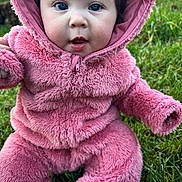 Jaylynn is registered to the contest to win money with this photo: baby, child, pink_outfit, fluffy_clothing, hood, grass, outdoor, cute, infant, seated, portrait, wide_eyes, expression, nature, young, person, warm_clothing, closeup, face, playful