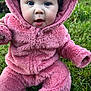 baby, child, pink_outfit, fluffy_clothing, hood, grass, outdoor, cute, infant, seated, portrait, wide_eyes, expression, nature, young, person, warm_clothing, closeup, face, playful