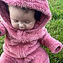 Jaylynn joined the competition — help win amazing prizes! baby, child, pink_clothing, onesie, hood, grass, outdoor, cute, infant, fluffy, sitting, face, person, nature, soft_texture, curly_hair, hoodie, young_child, casual_wear, daylight