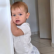 Angel a rejoint le concours — aidez-le/la à gagner de superbes lots ! toddler, child, indoor, white_shirt, blue_eyes, curious, leaning, wall, floor_tiles, door, short_hair, cute, baby_clothes, expression, person, young_child, home, standing, light, room