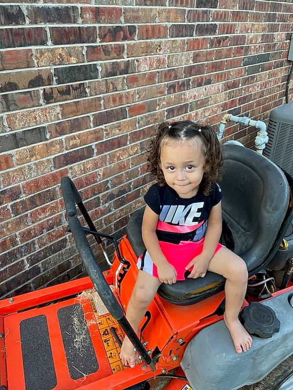 Navaia is registered to the contest to win money with this photo: auto_part, automotive_design, automotive_exterior, automotive_tire, automotive_wheel_system, baby_carriage, brick, brickwork, bumper, fun, joy, leisure, machine, motor_vehicle, orange, person, sitting, tire, toddler, tractor