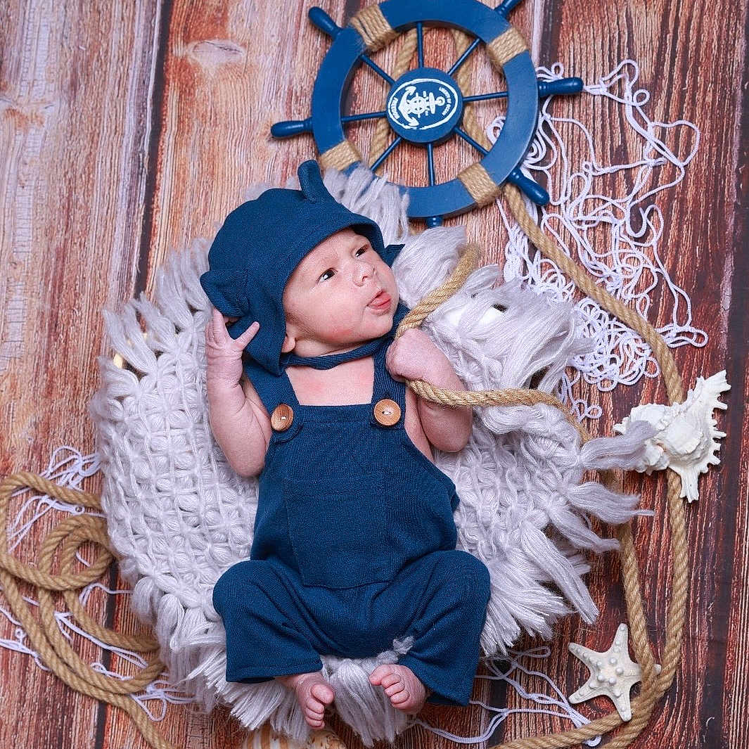 Damian joined the competition — help win amazing prizes! accessories, baby, bonnet, cap, clothing, costume, dress, face, hardwood, hat, head, homedecor, pajamas, pants, person, photography, portrait, purple, sitting, wood