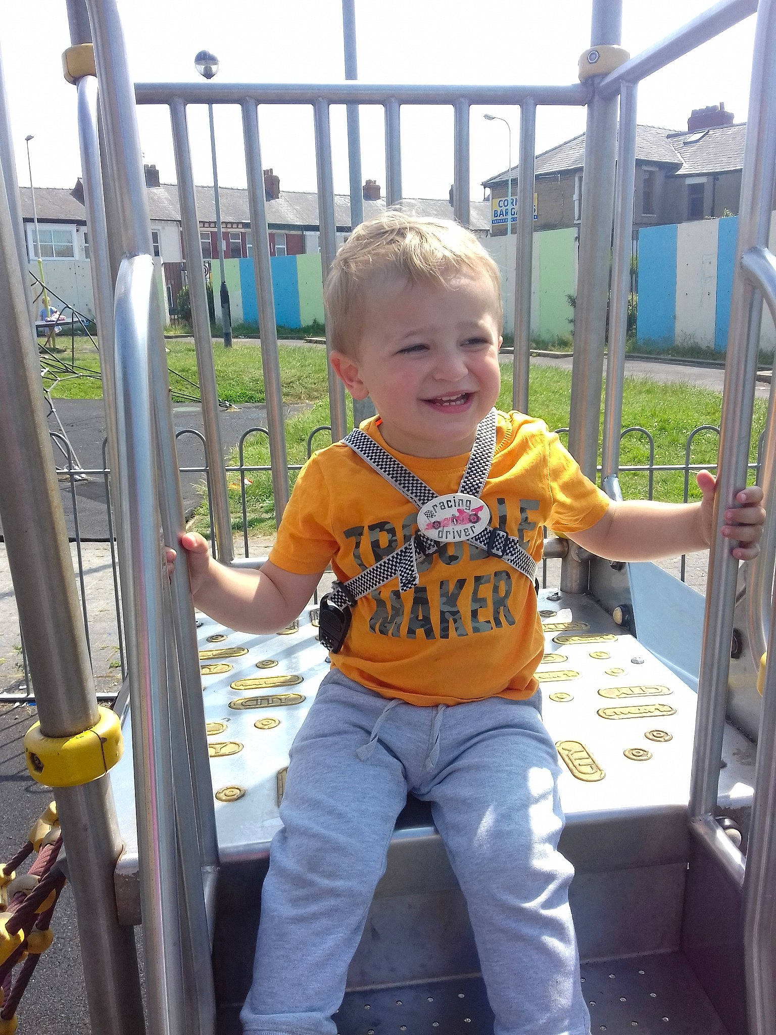 Kallum is registered to the contest to win money with this photo: boy, car, child, day, fun, jeans, joy, outdoor_play_equipment, person, play, playground, product, public_space, recreation, smile, standing, toddler, vacation, vehicle