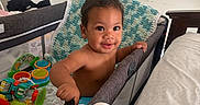 Michael joined the competition — help win amazing prizes! baby, bed, blanket, child, colorful, crawling, curly_hair, cute, diaper, face, furniture, happy, home, indoor, infant, person, playpen, plush, smile, toy