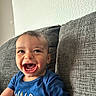 baby, child, smiling, happy, blue_shirt, fox_design, couch, gray_couch, indoor, portrait, cute, young_child, textile_texture, patterned_background, infant, person, sitting, cheerful, closeup, casual_clothing