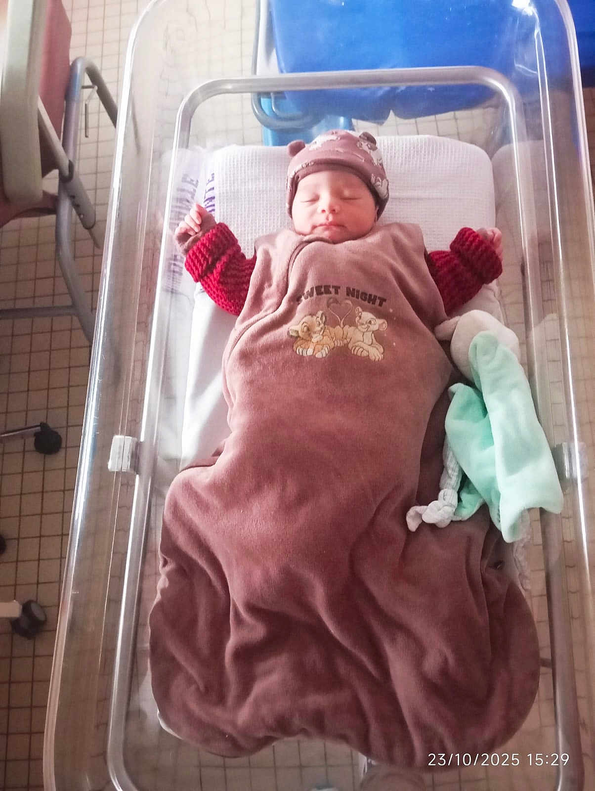 Noâm participe au concours pour gagner de l'argent avec cette photo : newborn, baby, sleeping, hospital, bassinet, blanket, hat, clothing, bed, infant, tiled_floor, person, indoors, soft_light, quiet, peaceful, wrapped, baby_bed, resting, cozy