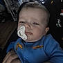 Hudson joined the competition — help win amazing prizes! baby, pacifier, blue_clothing, infant, person, hand, indoor, sleepy, face, portrait, child, holding, soft_lighting, home, cluttered_background, young_child, cute, racing_logo, closeup, expression