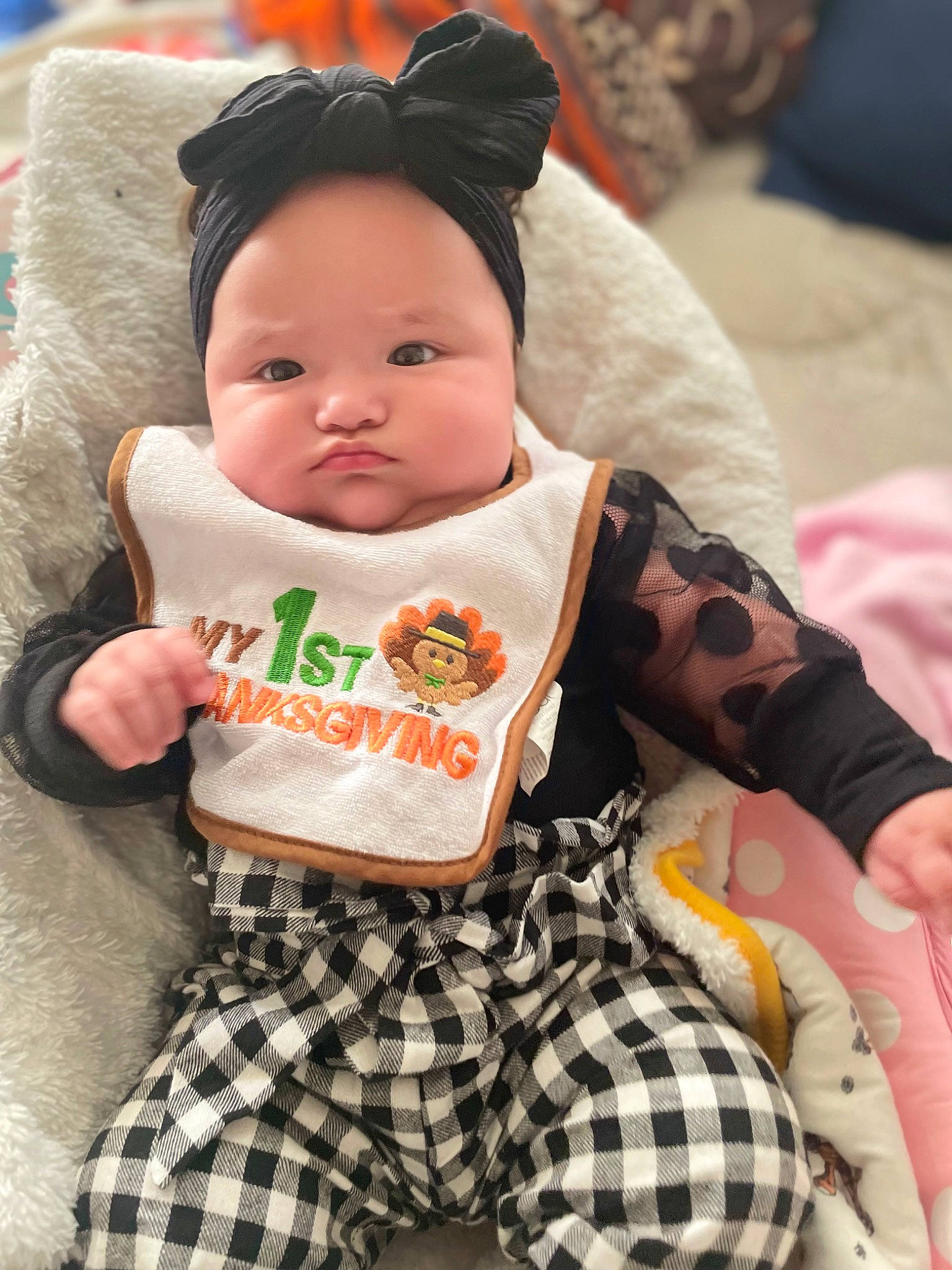 Ariyah is registered to the contest to win money with this photo: baby, baby_toddler_clothing, cheek, child, comfort, face, fun, happy, linens, outerwear, pattern, person, pink, sitting, skin, sleeve, t_shirt, tartan, textile, toddler